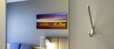 Habitación de hotel con cama, almohadas, mesita de noche, lámpara y un cuadro en la pared.