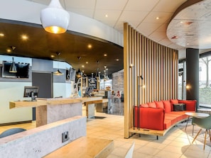 Un intérieur moderne comprenant un comptoir d’accueil, un espace détente et une grande fenêtre.