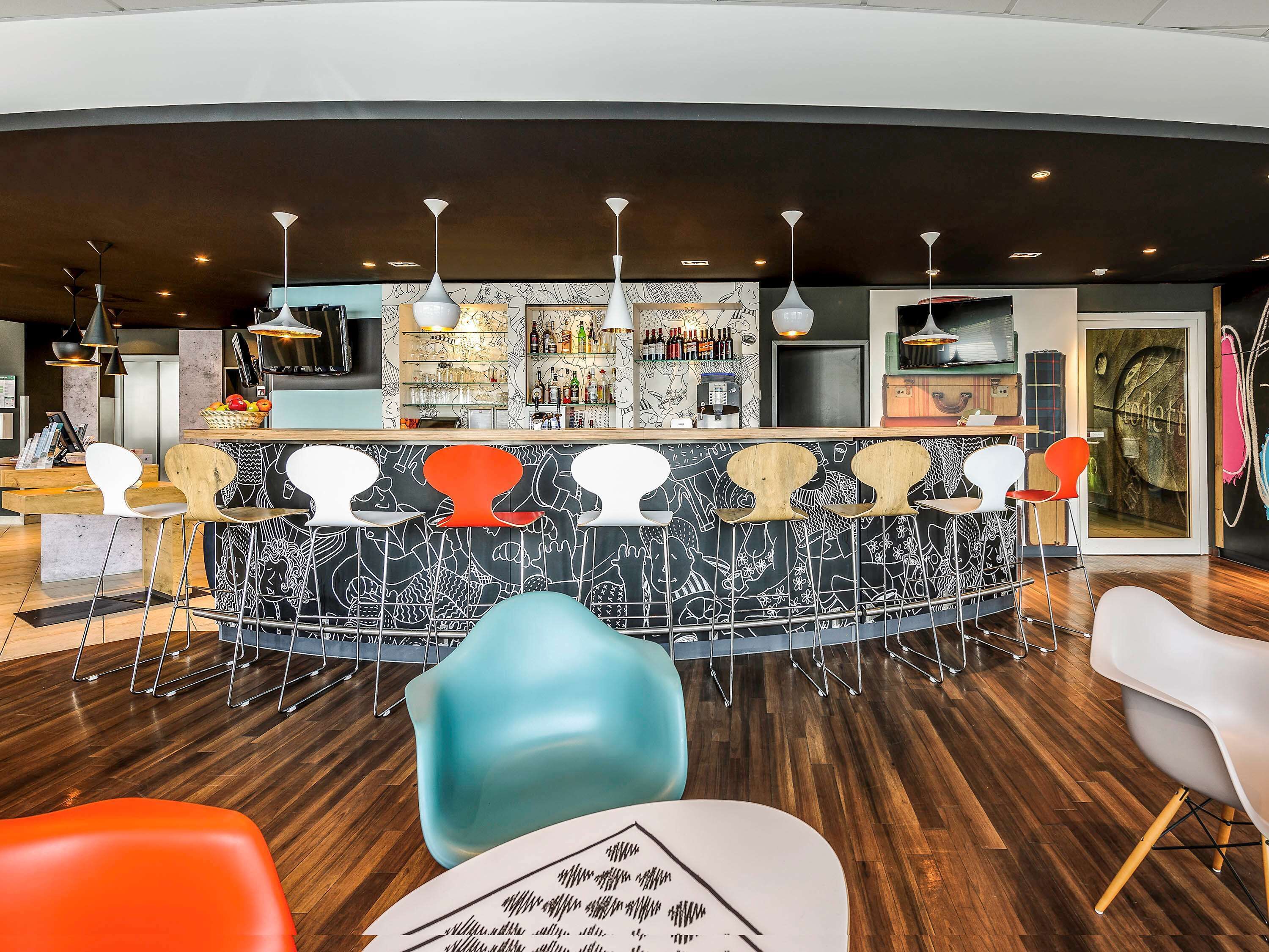 A modern bar area with a central island, bar stools, and a variety of bottles and glasses on shelves.