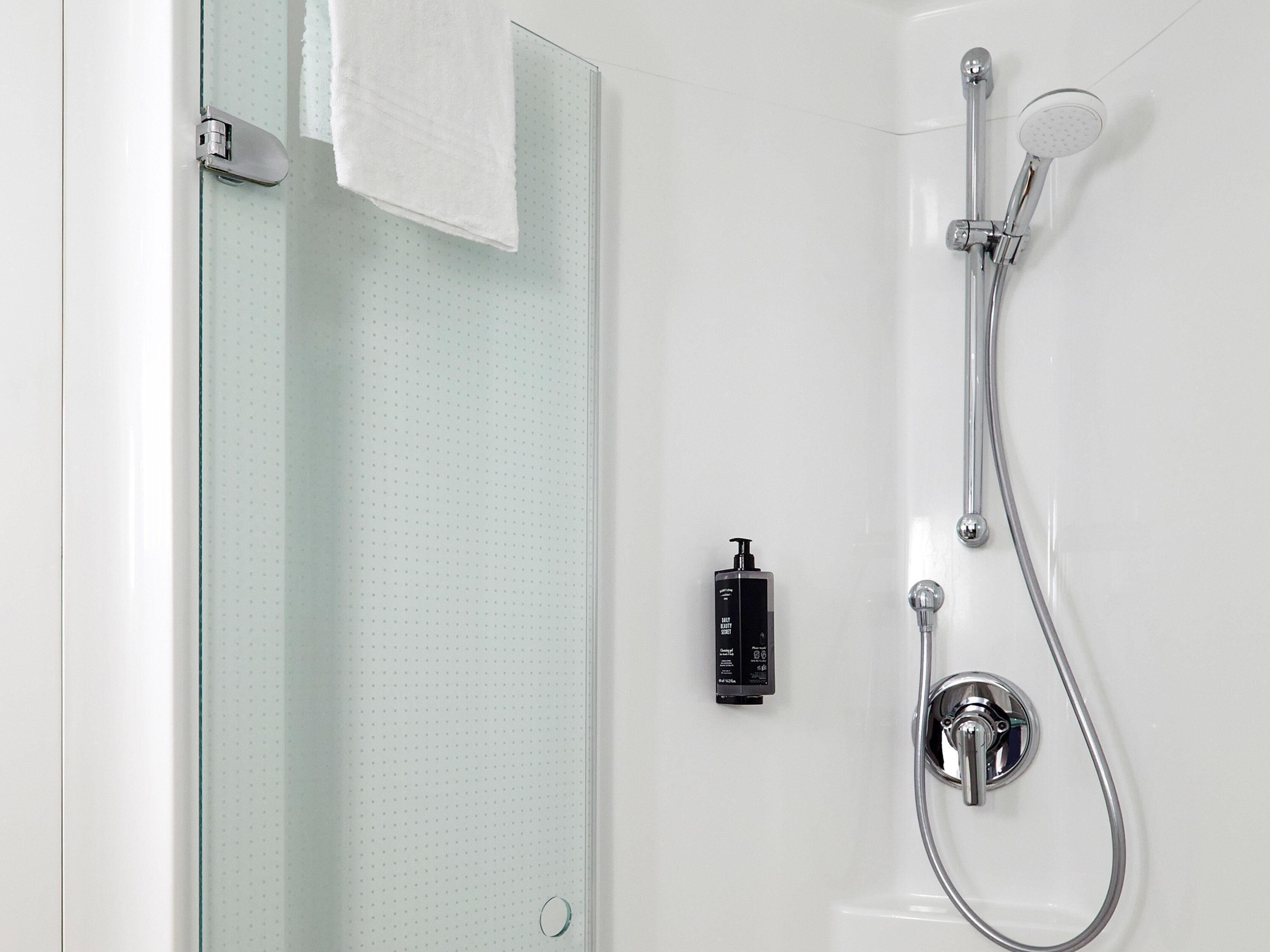 A modern shower with a handheld showerhead and a wall-mounted faucet.