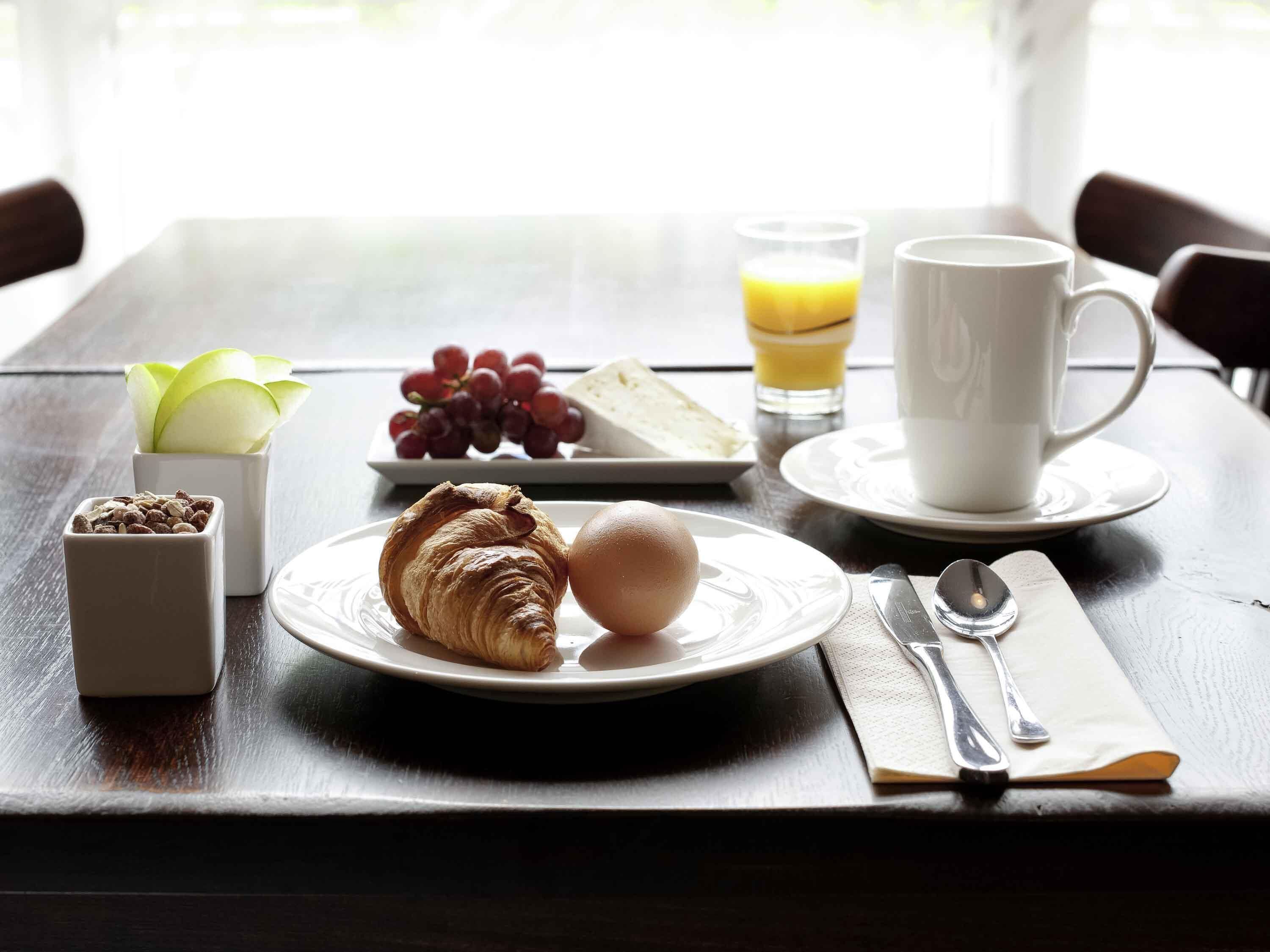 Ein Frühstückstisch mit Croissants, Eiern, Trauben, Käse und Saft.