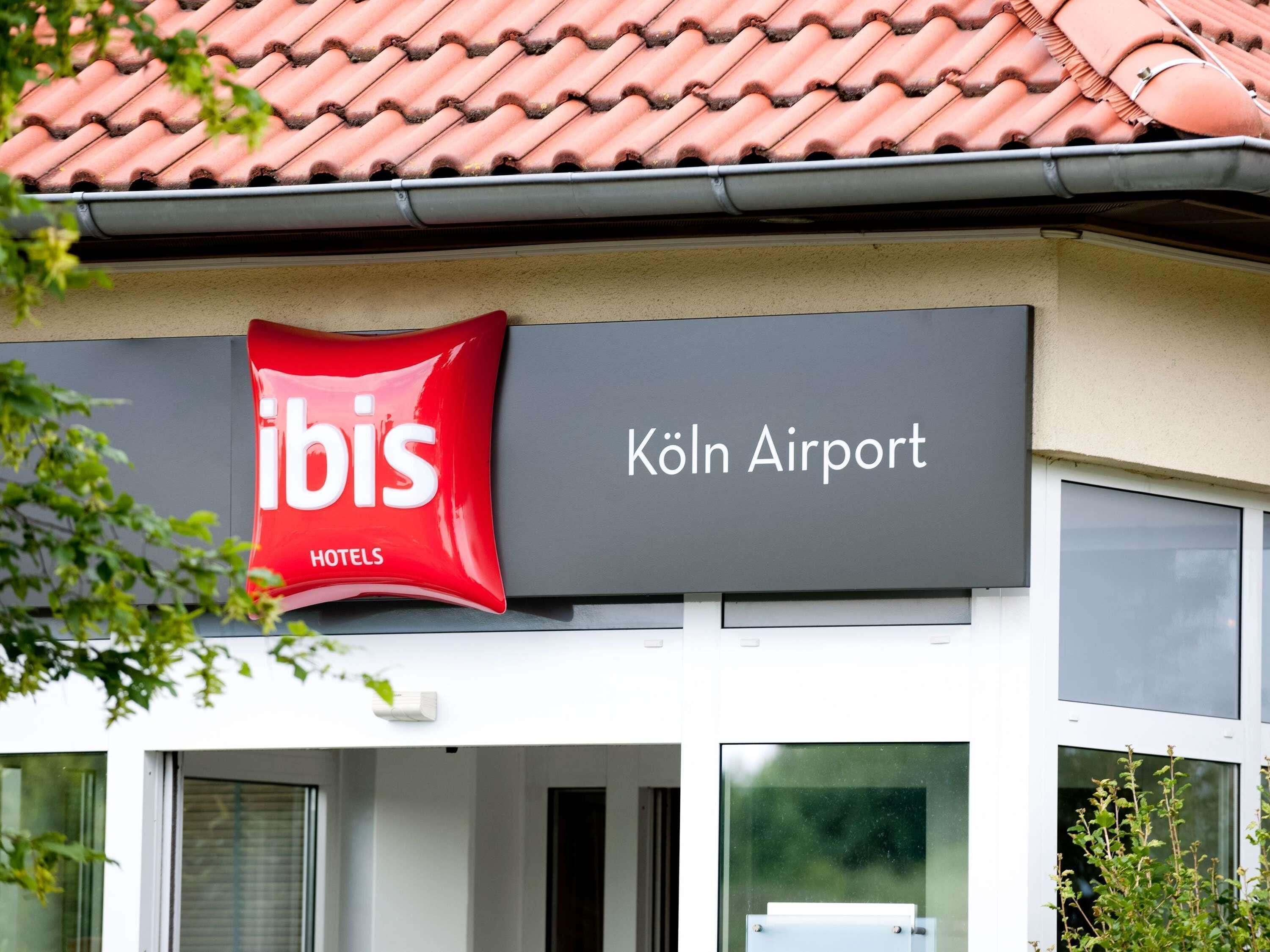Une enseigne d’hôtel indiquant « ibis HOTELS » et « Aéroport de Cologne », ce qui permet de situer l’établissement.