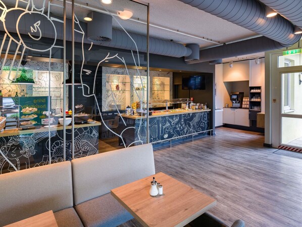 A modern restaurant interior with a counter, seating area, and a television screen.