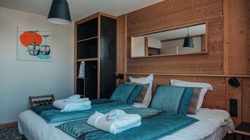 Une chambre avec un grand lit, une armoire intégrée, un miroir et un luminaire au plafond.