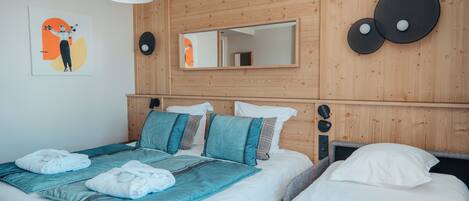 Una habitación de hotel con cabecera de madera, un espejo grande y una cama con ropa de cama azul y blanca.