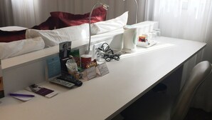 A hotel room with a desk, chair, and a bed with red bedding. - Mercure São Paulo Paulista Hotel (São Paulo)