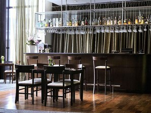 Un espace bar avec des chaises en bois et un comptoir où sont exposées différentes bouteilles.