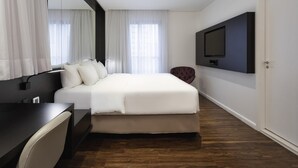 A modern hotel room with a large bed, a desk, a chair, a TV mounted on the wall, and a door. - Mercure São Paulo Paulista Hotel (São Paulo)