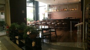 A restaurant with a brick wall, wooden tables, and chairs. There are potted plants and a fire feature. - Mercure São Paulo Paulista Hotel (São Paulo)