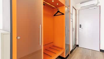 Un vestidor con interior naranja, una barra para colgar ropa y una puerta blanca con picaporte.