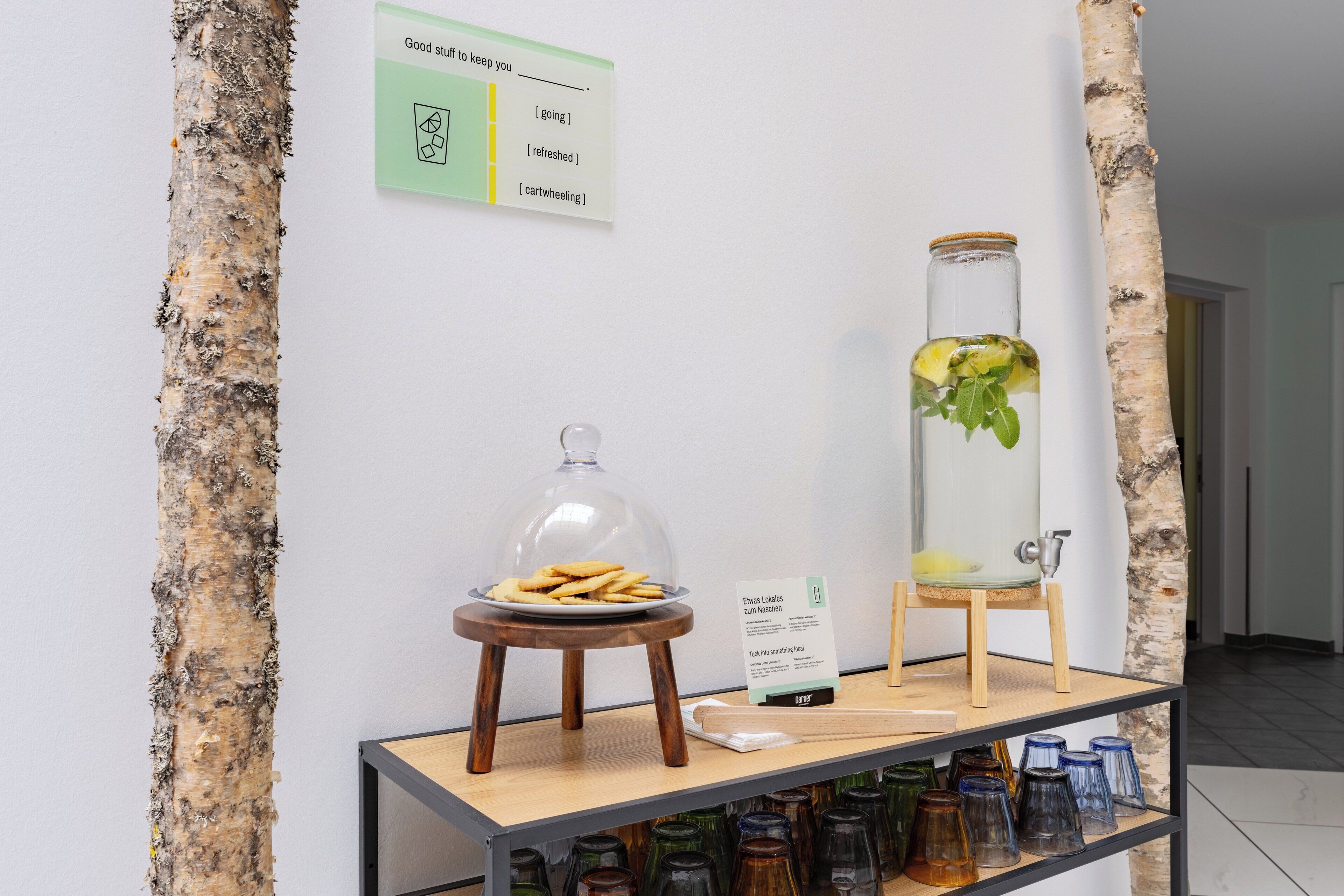 Une présentation comprenant un bocal en verre contenant une plante, une assiette de biscuits et un panneau avec du texte.