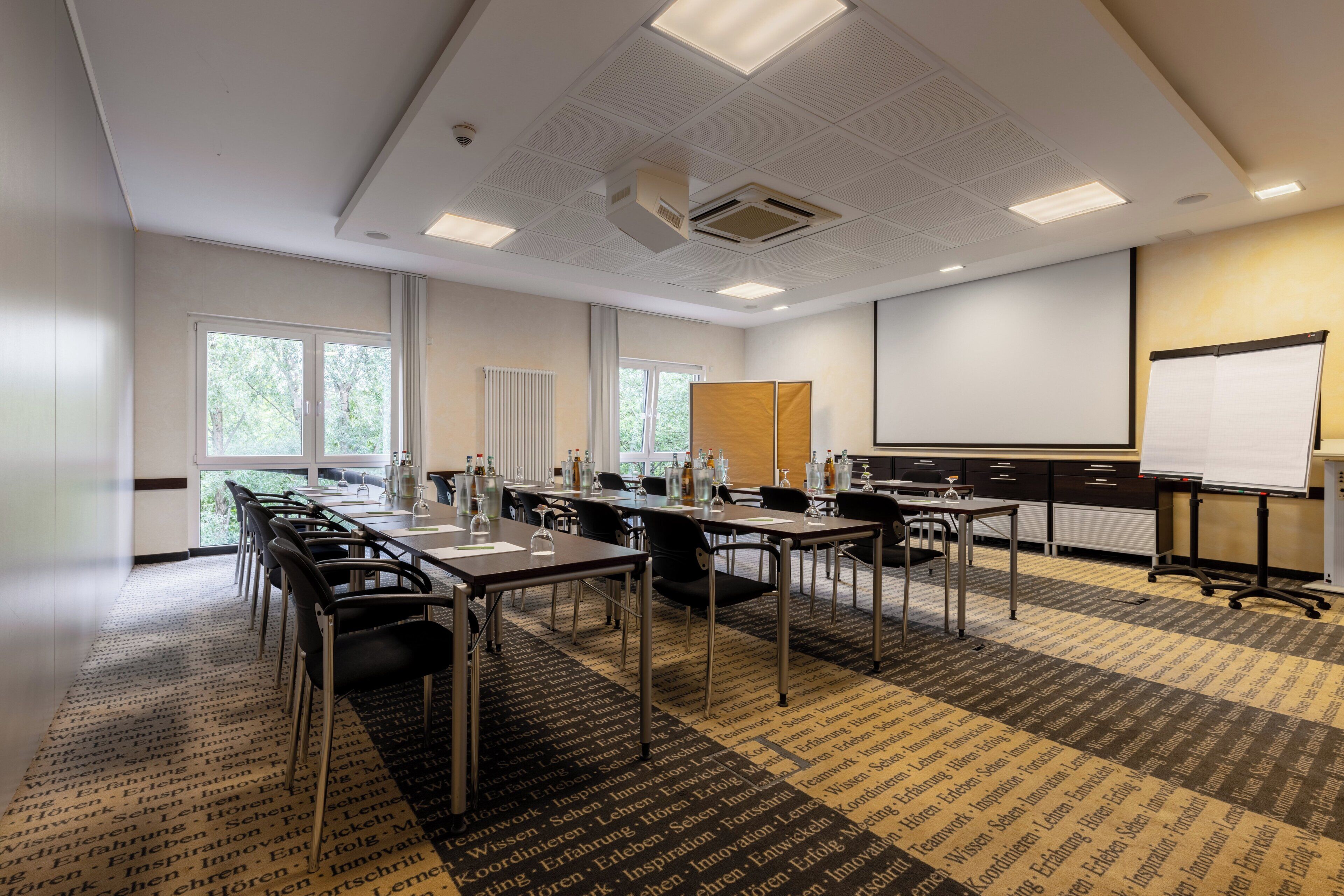 A conference room with a long table, chairs, a projector screen, and a whiteboard.