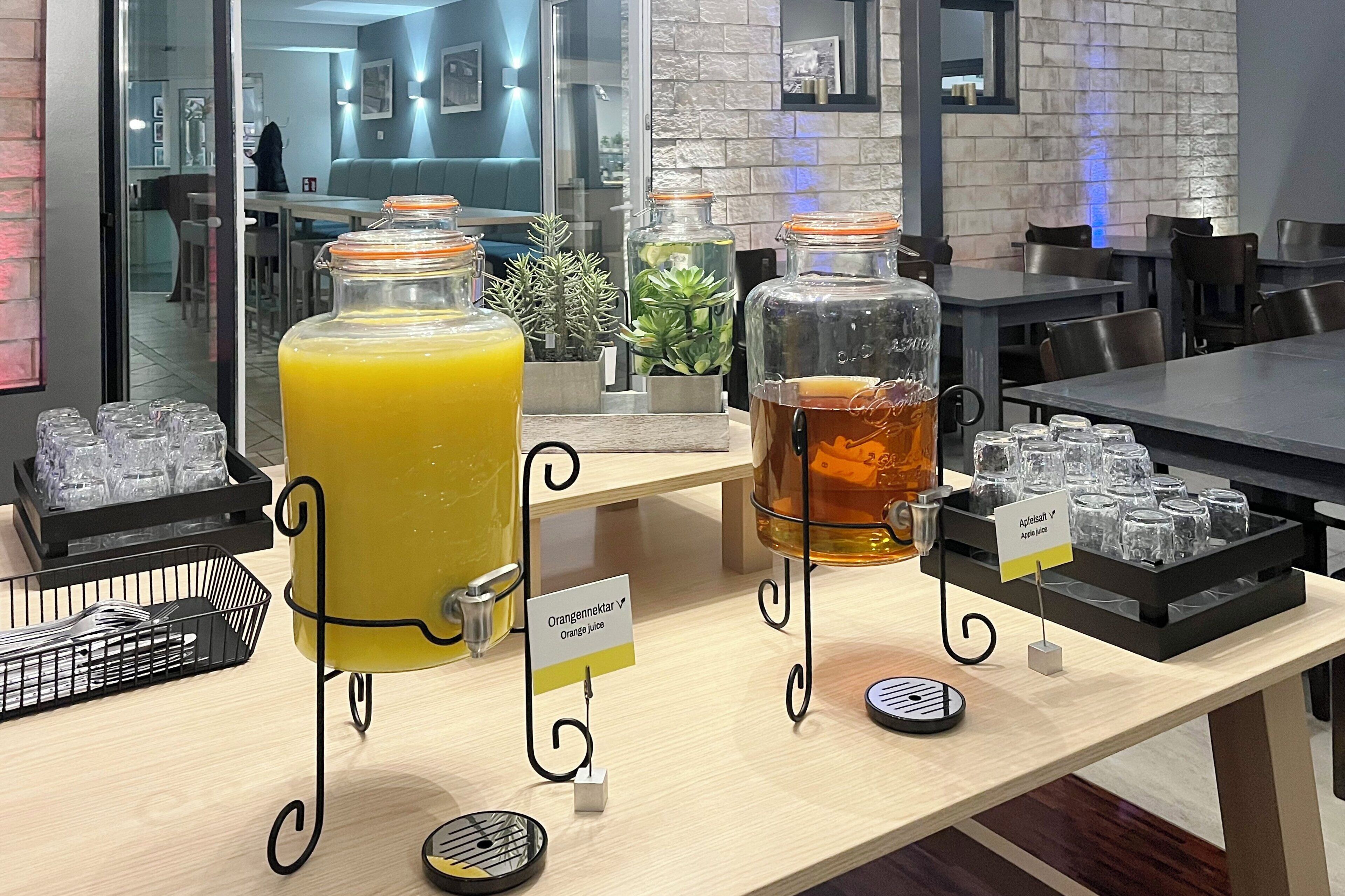 A juice bar with two large dispensers, one for orange juice and one for apple juice, and a sign indicating the type of juice.
