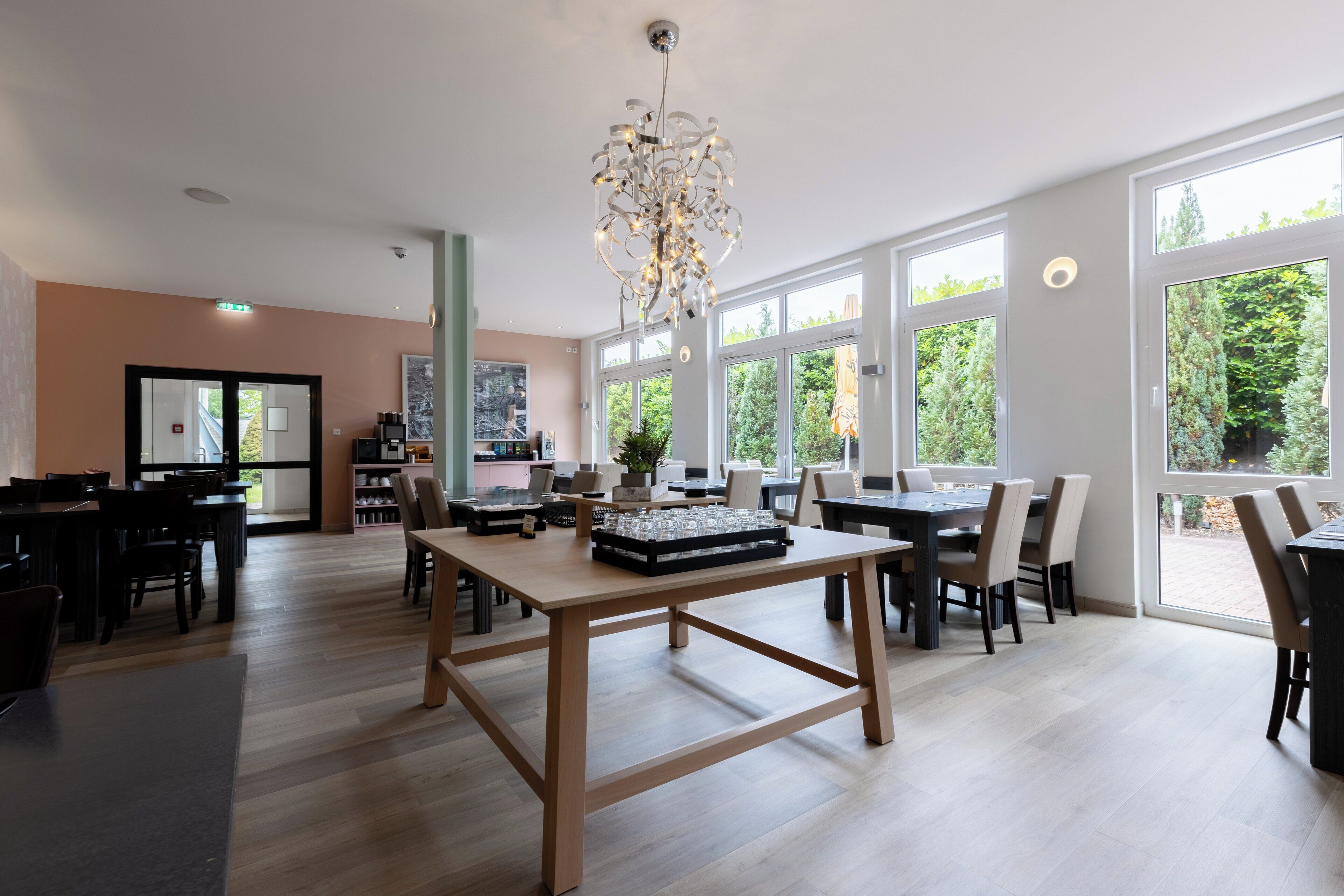 A spacious dining area with large windows, a chandelier, and a variety of seating arrangements.