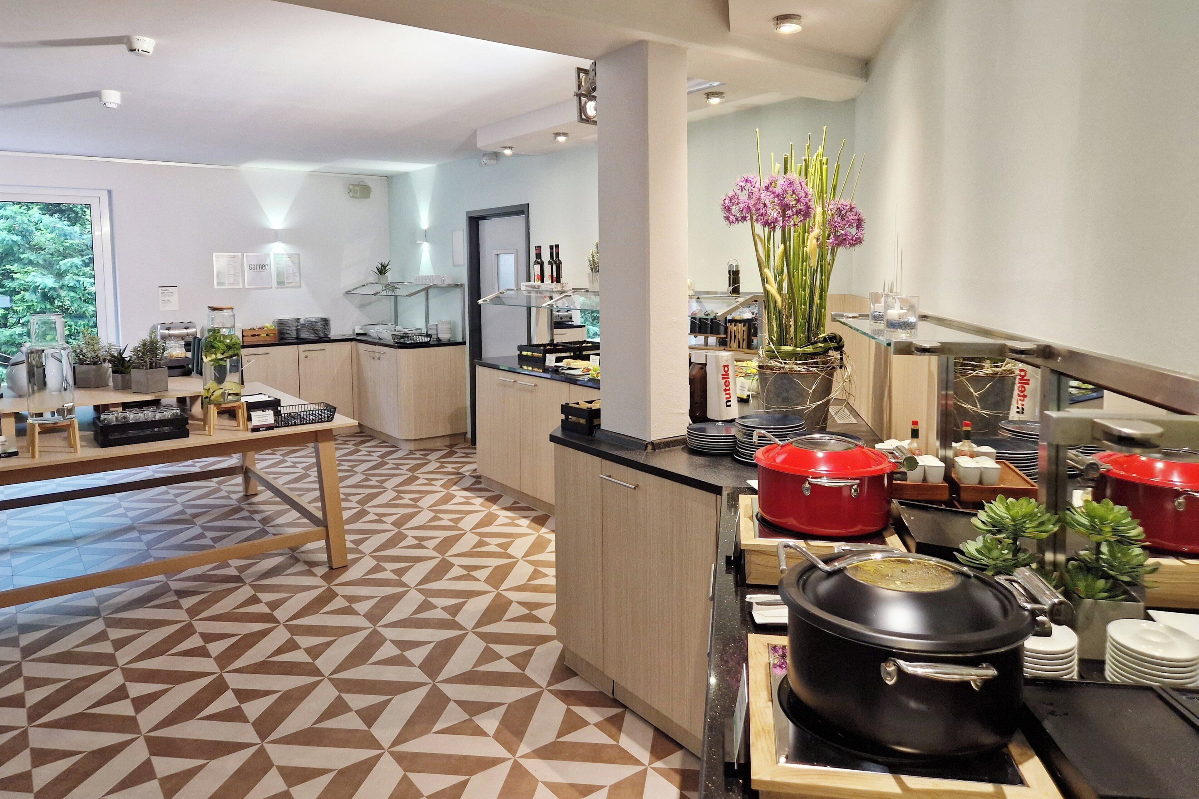 A modern kitchen with geometric patterned flooring, a central island, and red cooking pots.