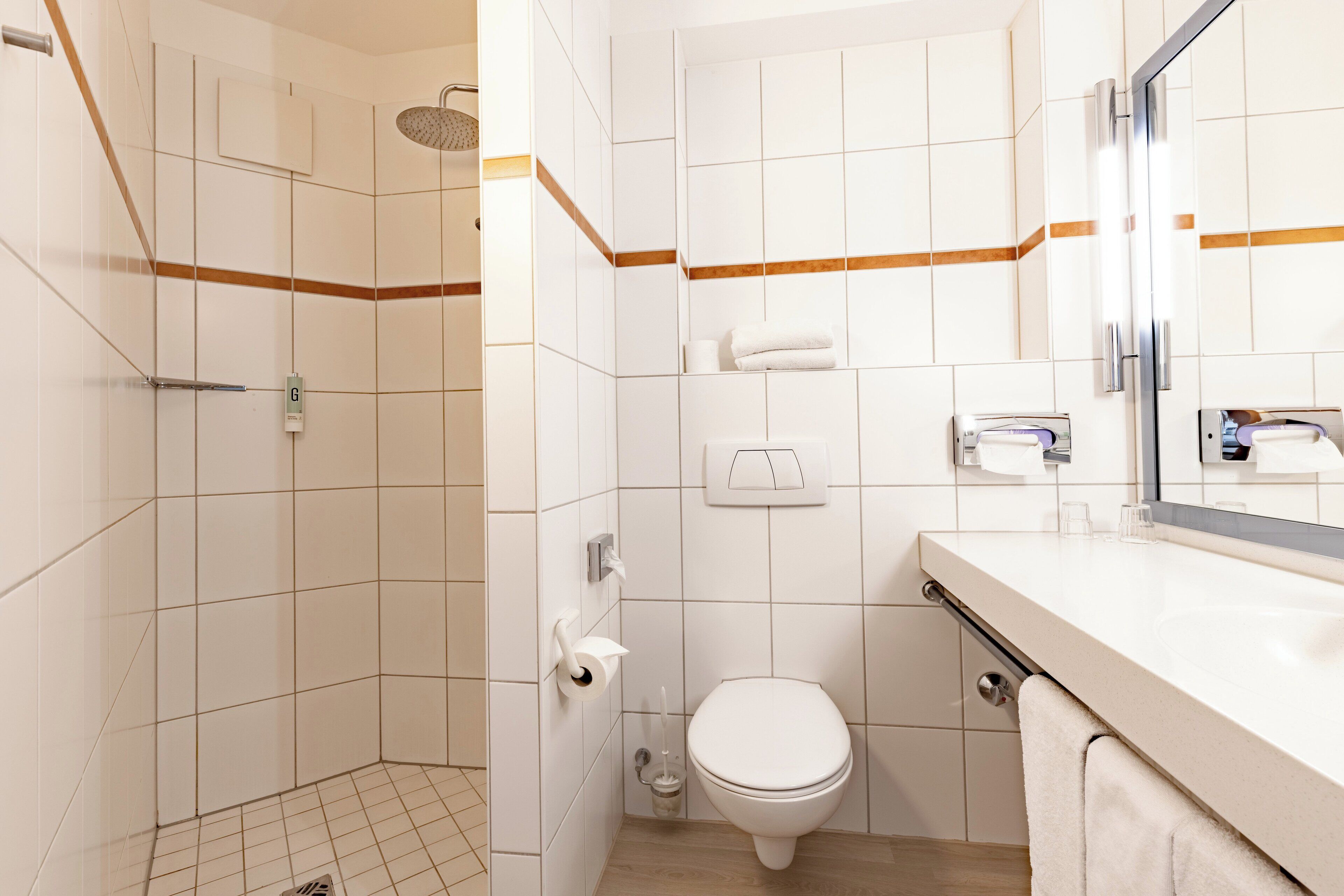 A modern bathroom with a shower, toilet, and sink.