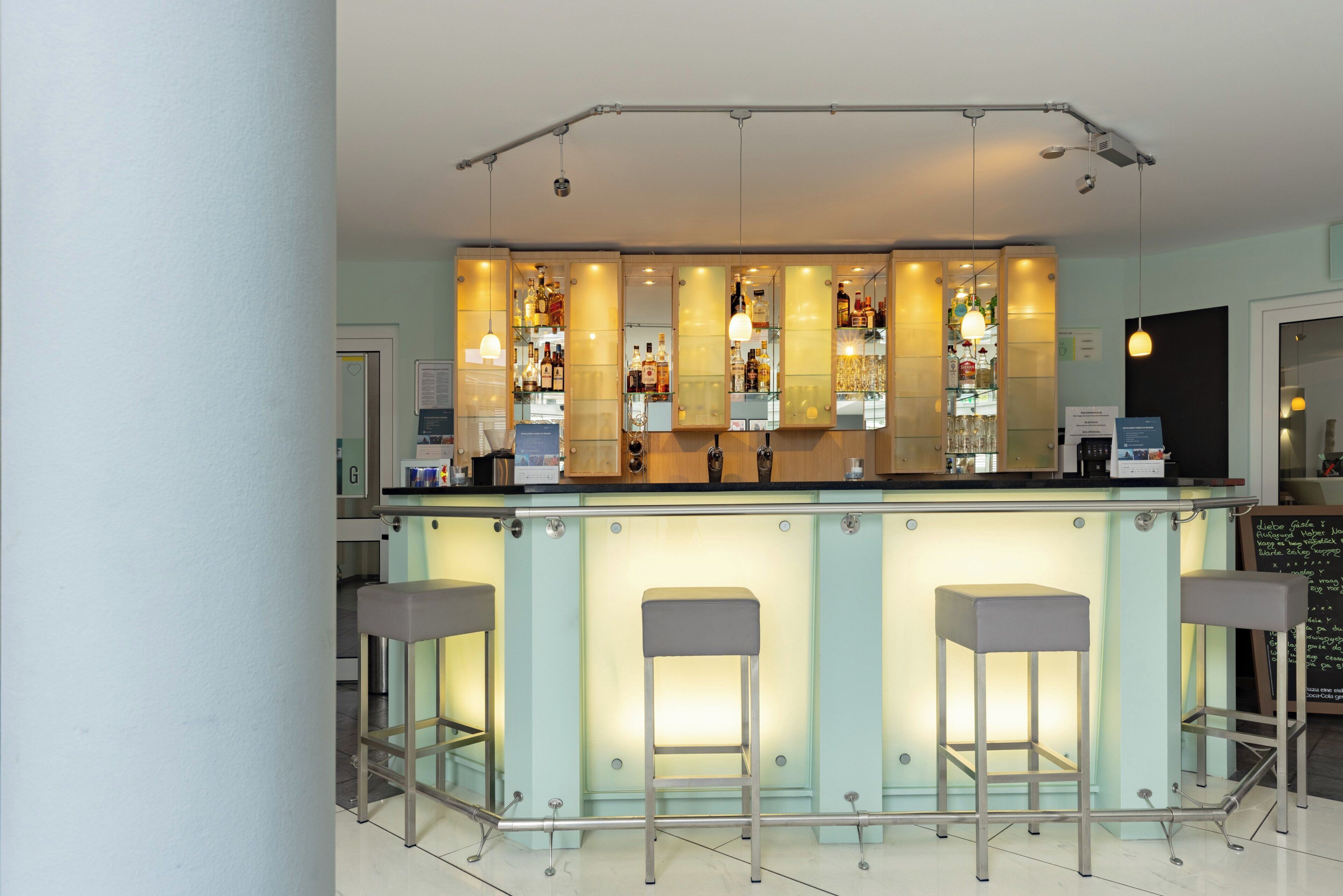 A bar area with a counter, stools, and shelves of bottles.