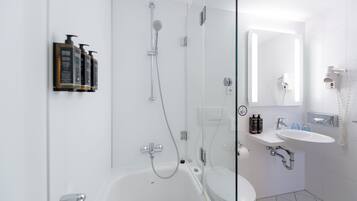 A modern bathroom with a glass shower enclosure, a white bathtub, a sink, and a toilet.