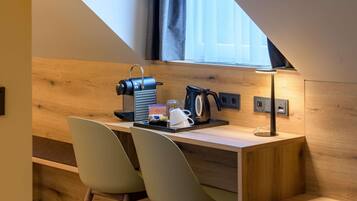 Une petite cuisine moderne et fonctionnelle, dotée d’une machine à café intégrée, d’une bouilloire et d’un petit coin repas avec deux chaises.