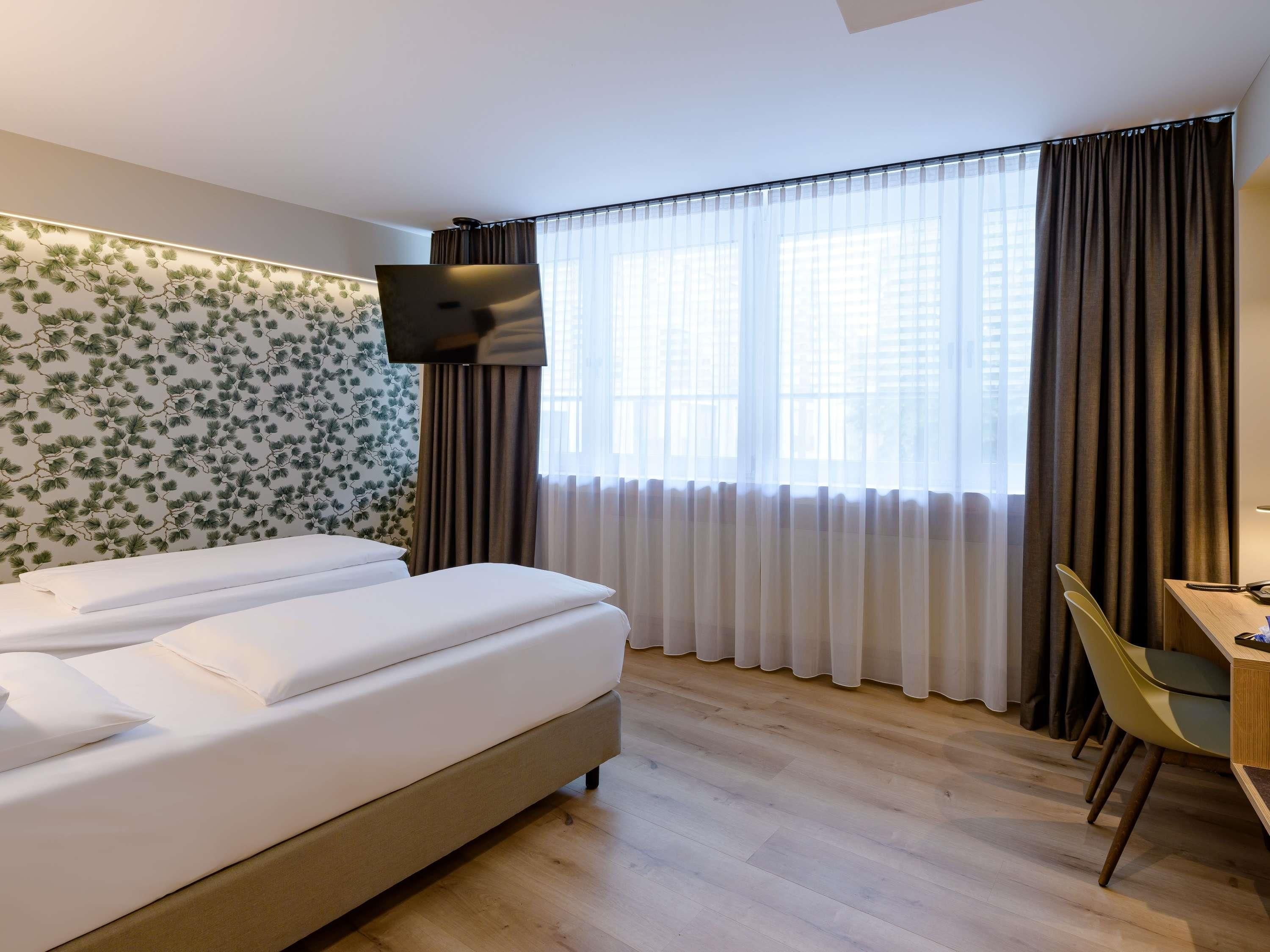A hotel room with a bed, a desk, and a TV.