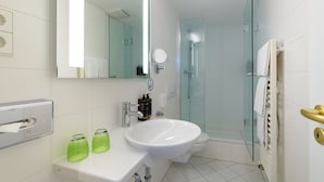 A modern bathroom with a white sink, mirror, and glass shower enclosure. - Mercure Hotel München Altstadt (Munich)