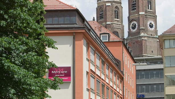 A building with a Mercure hotel sign, a clock tower, and a dome. - Mercure Hotel München Altstadt (Munich)
