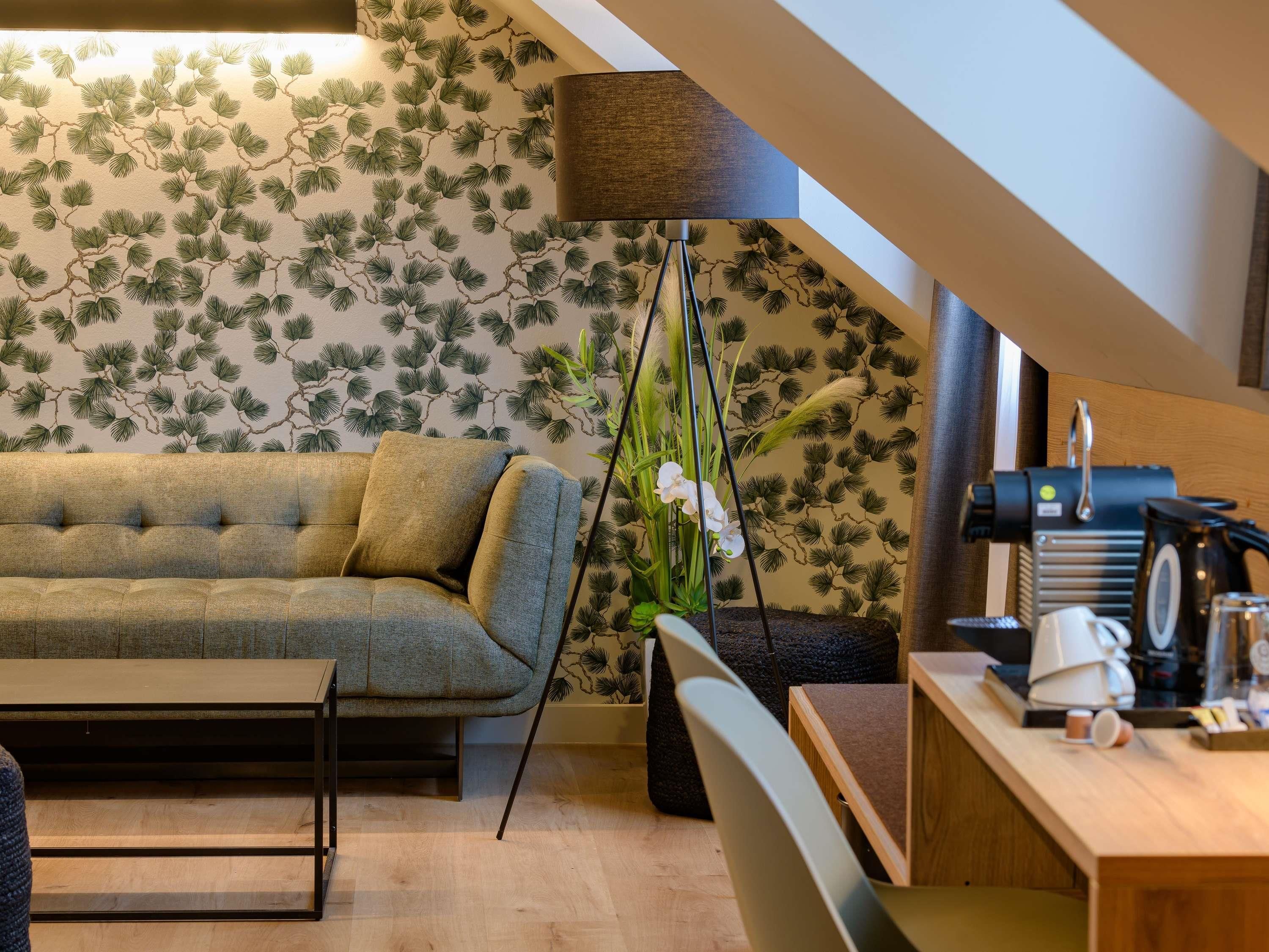 Ein gemütliches Wohnzimmer mit einer Couch, einem Couchtisch, einer Stehlampe und einem Schreibtisch mit Kaffeemaschine.