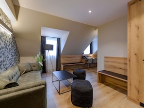 Una habitación estilo loft moderna con sofá, reposapiés y zona de comedor con mesa y sillas.