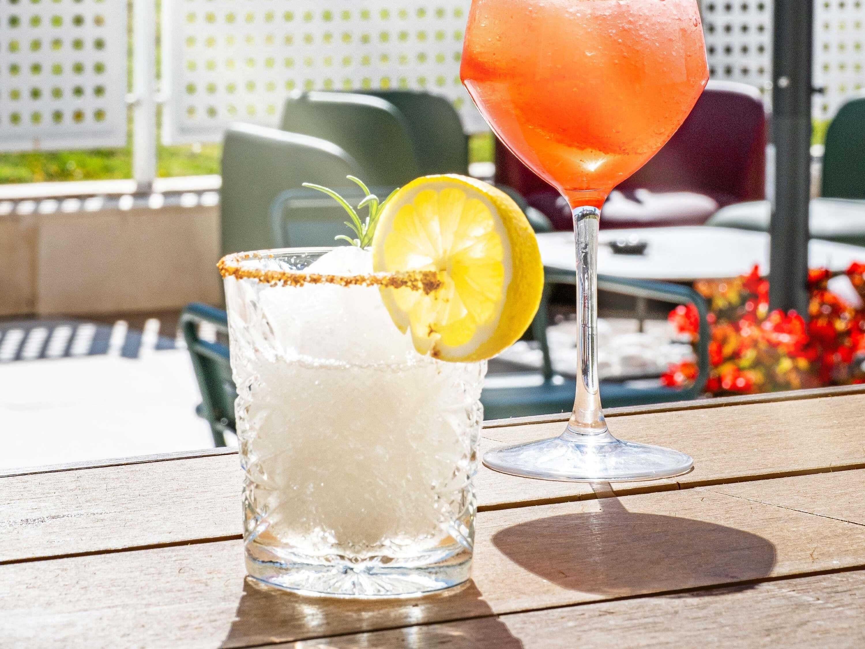 Dos vasos de bebidas sobre una mesa de madera al aire libre.