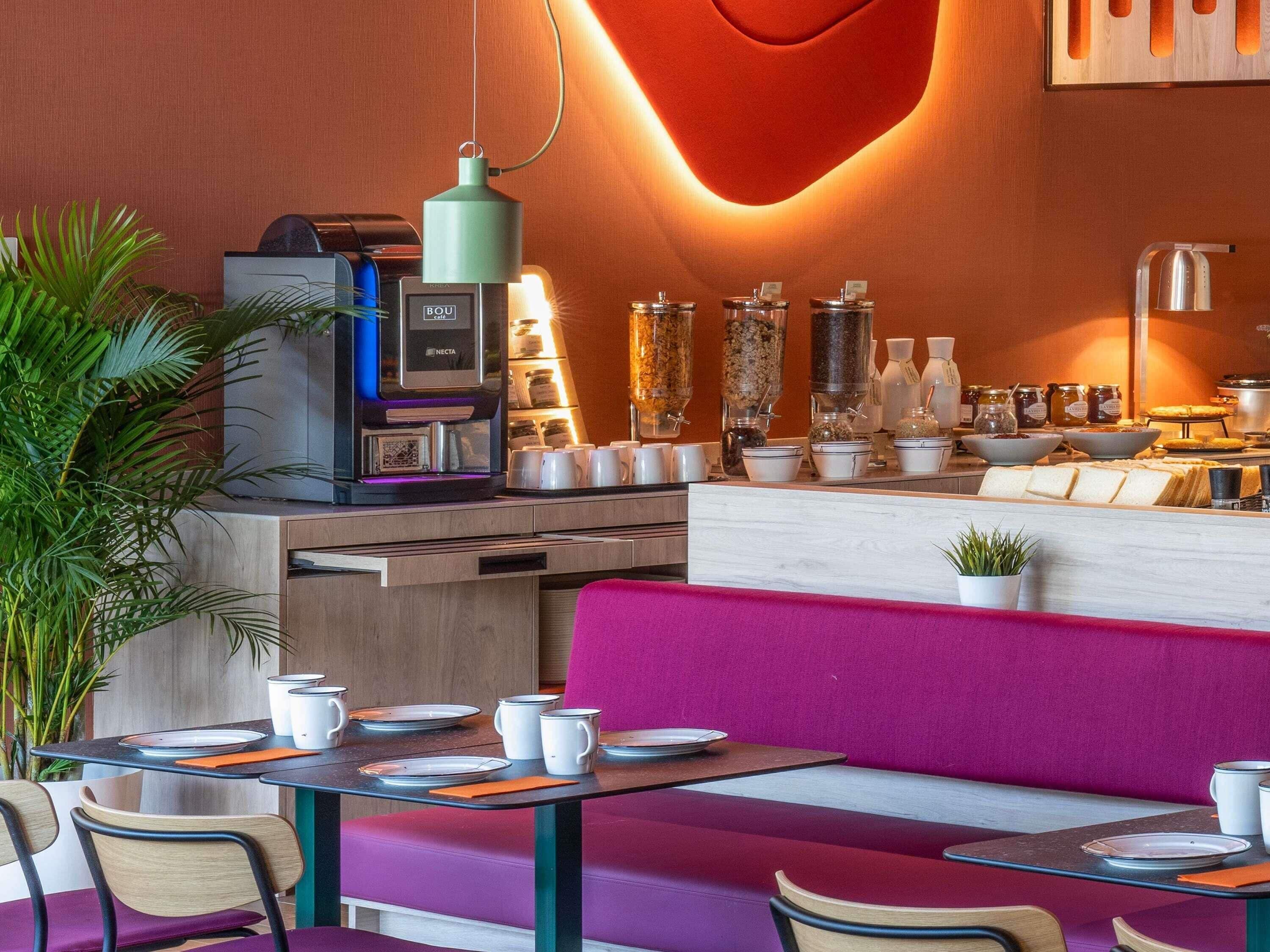 Ein modernes Café mit einer Kaffeemaschine, Sitzgelegenheiten und verschiedenen Speisen- und Getränkebehältern.