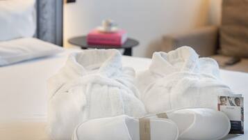 Una habitación de hotel con una cama bien hecha, una mesita de noche con una caja rosa y una lámpara.
