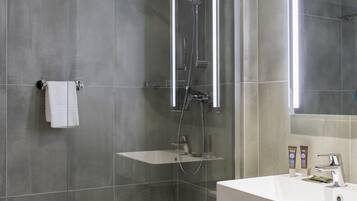 Un baño moderno con ducha envuelta en vidrio, un lavabo blanco y un espejo.