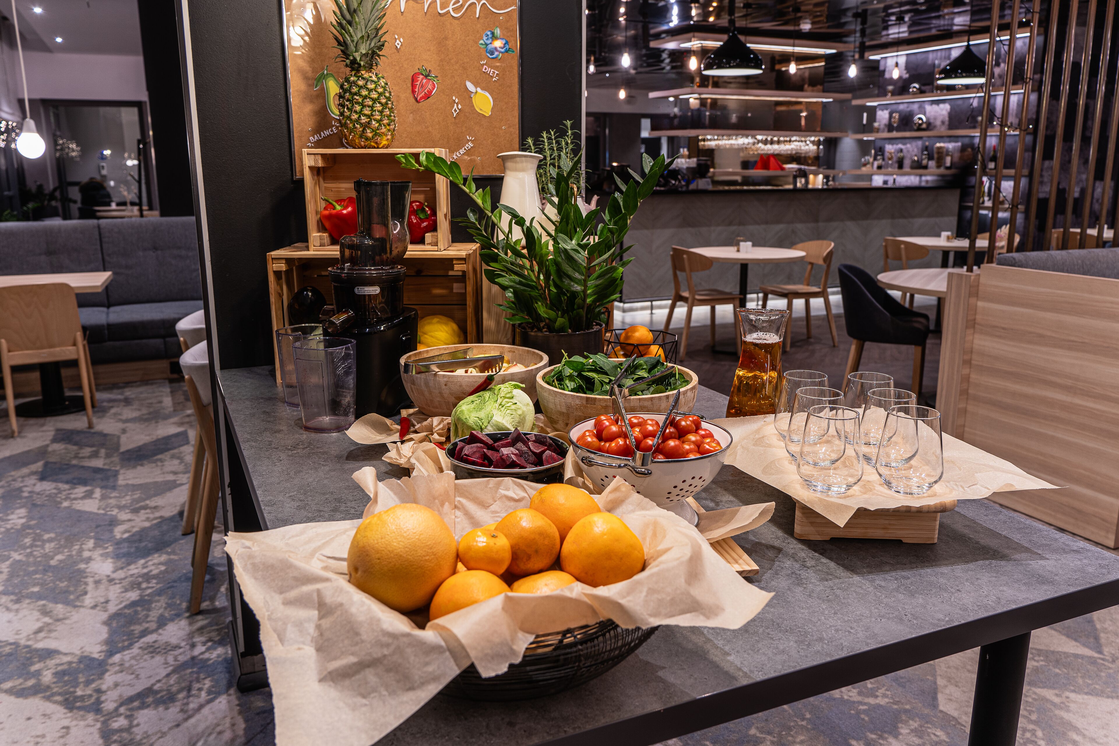 A dining area with a table set with oranges, tomatoes, and a salad, and a bar in the background.