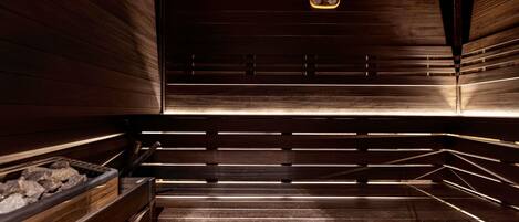 A sauna with wooden walls and benches, a bench with a heater, and a control panel.
