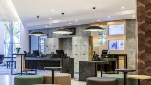 Eine moderne Hotelhalle mit einer Rezeption, Sitzbereichen und einem großen Fenster.