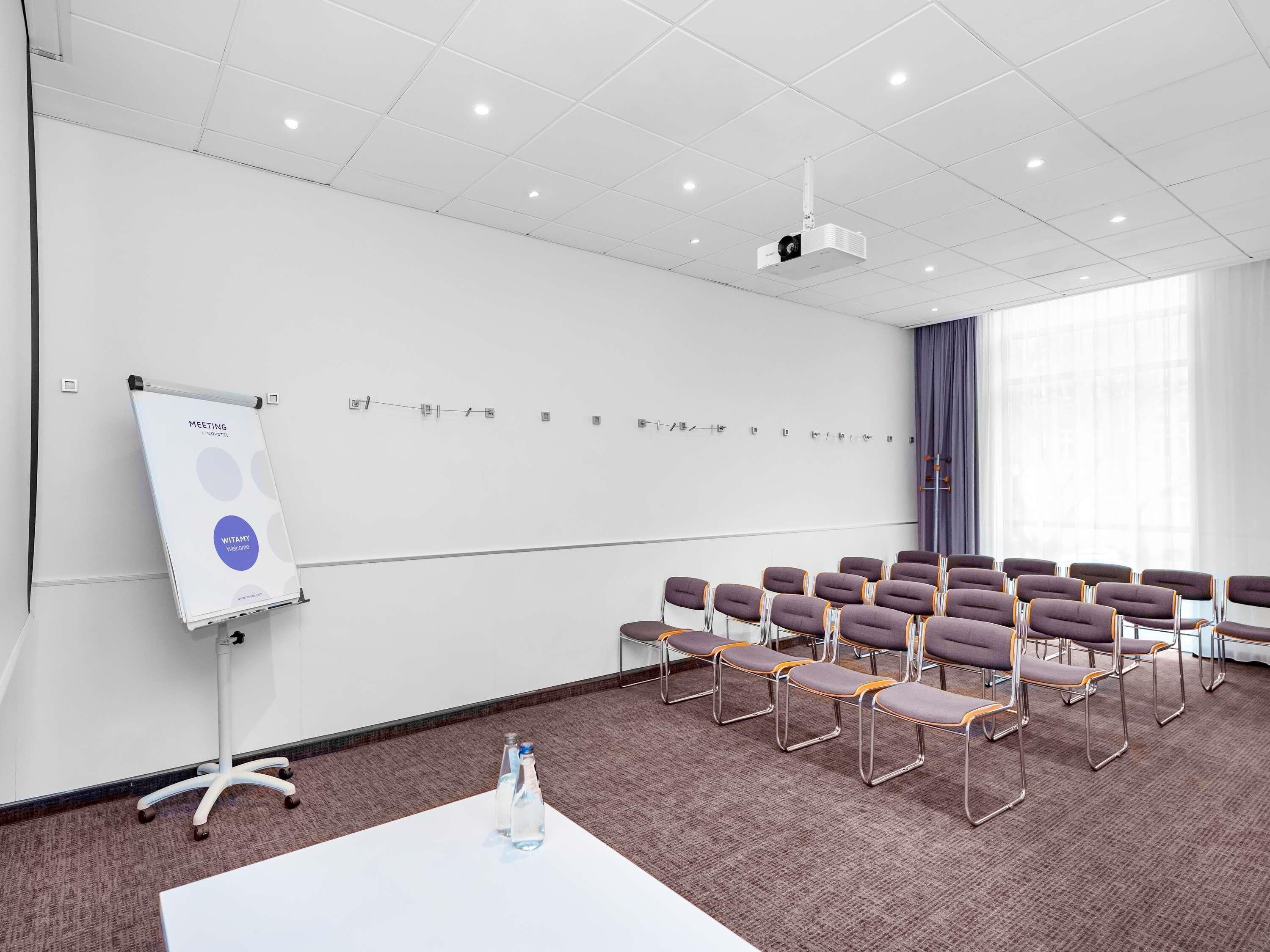A conference room with a whiteboard, projector, and rows of chairs.
