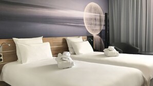 Ein Hotelzimmer mit zwei Betten, weißer Bettwäsche und Handtüchern.