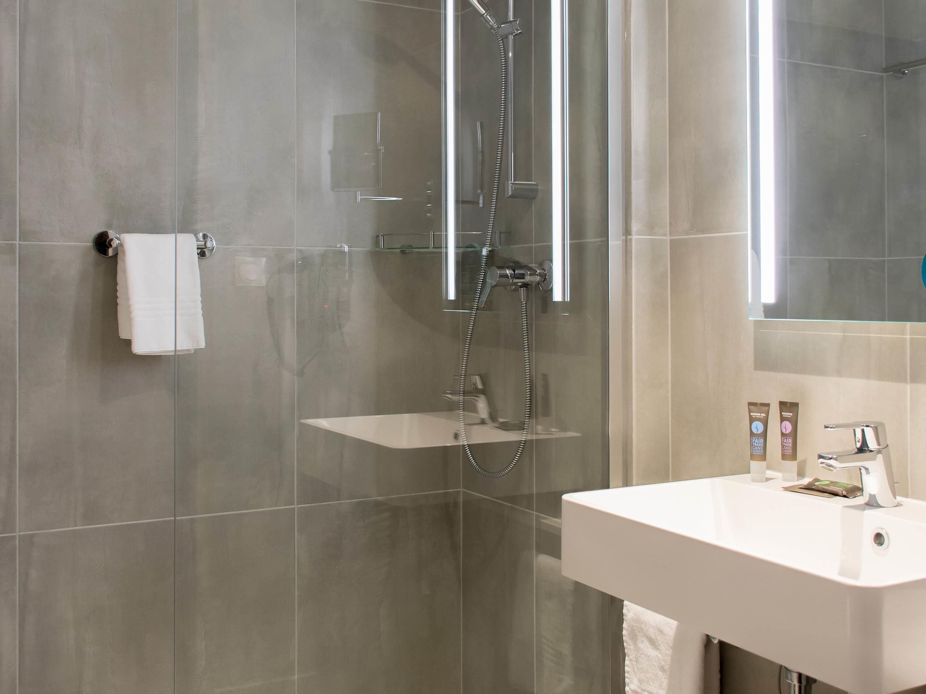 A modern bathroom with a glass-enclosed shower, a white sink, and a mirror above the sink.