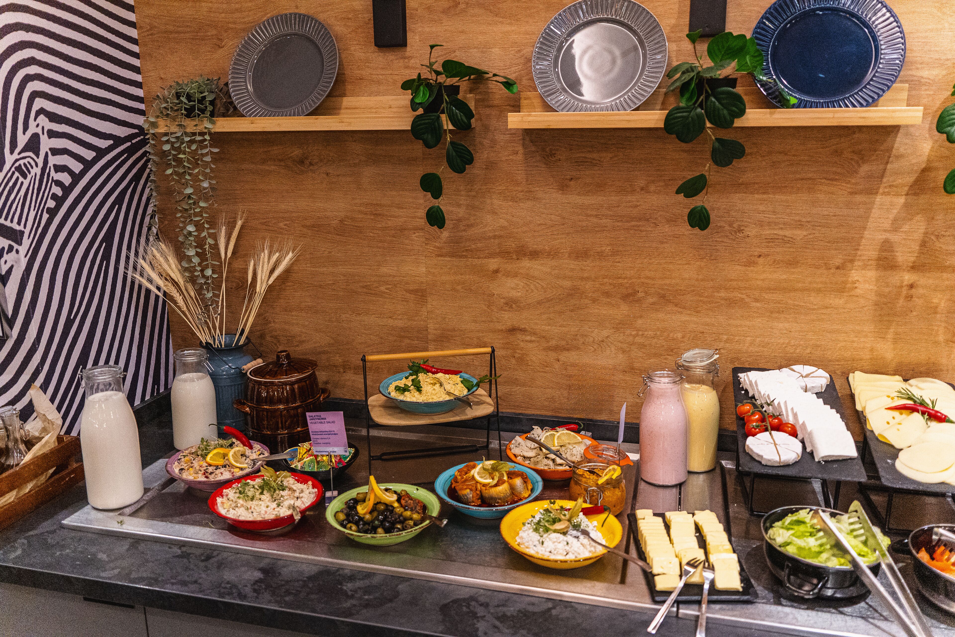 A buffet with various food items and drinks, including plates, bowls, and bottles.