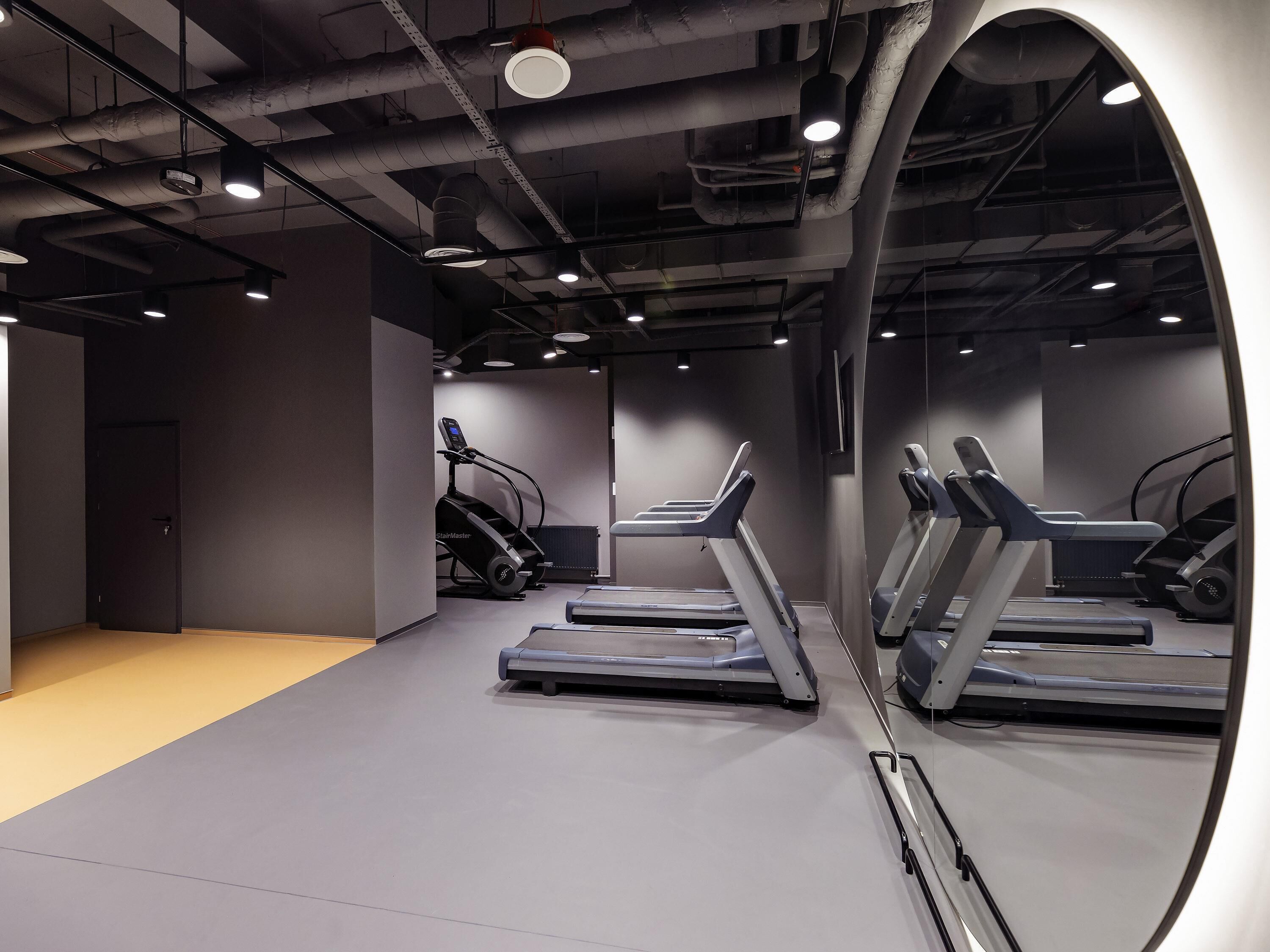 A gym with treadmills and a stair climber, with a door and a radiator in the background.