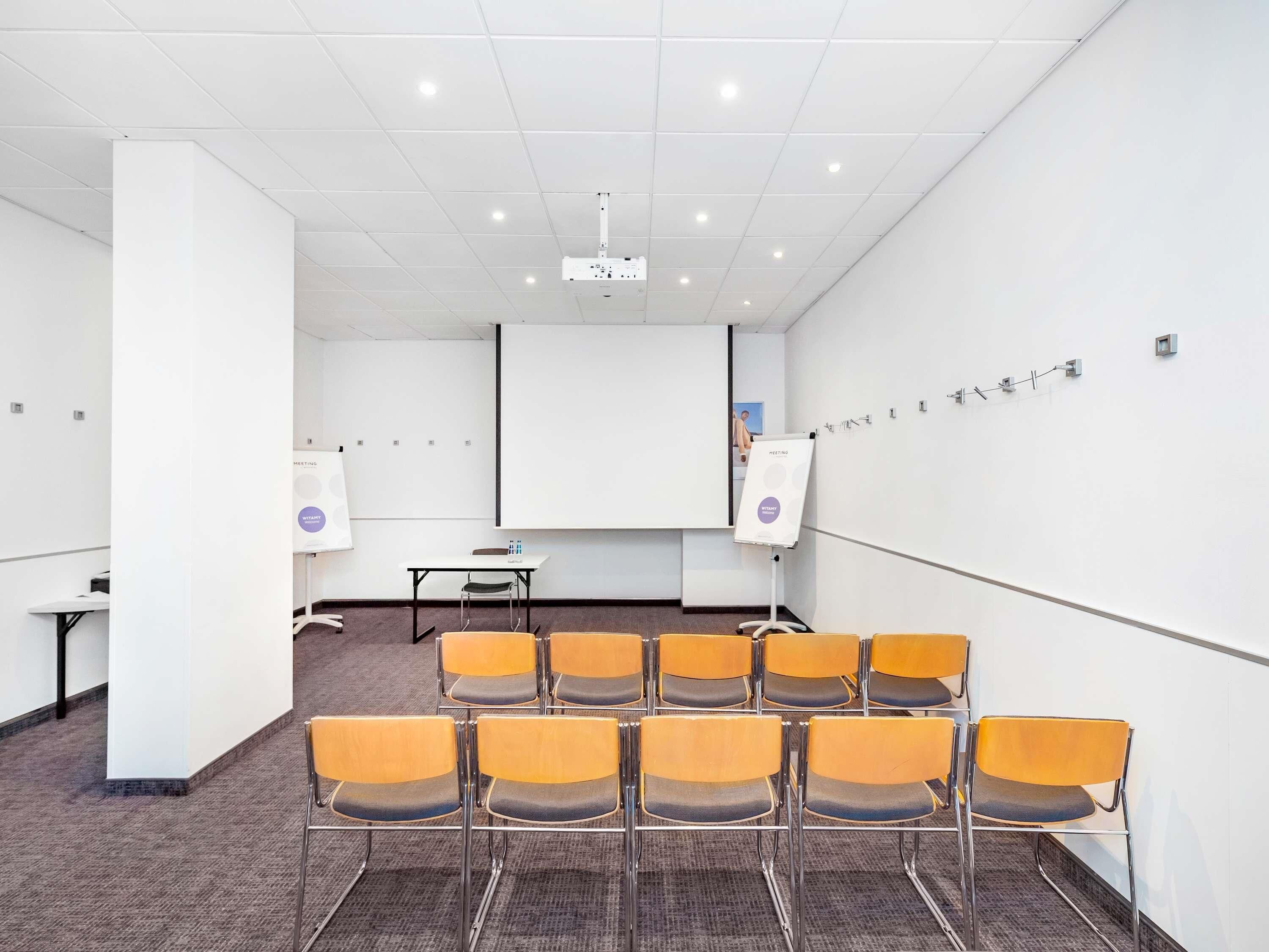 A conference room with a whiteboard, projector, and rows of chairs.