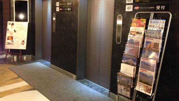 An elevator area with floor indicators, a sign for the 6F and 4F, and a rack of brochures. - APA Hotel TKP Sapporo Ekimae (Sapporo)