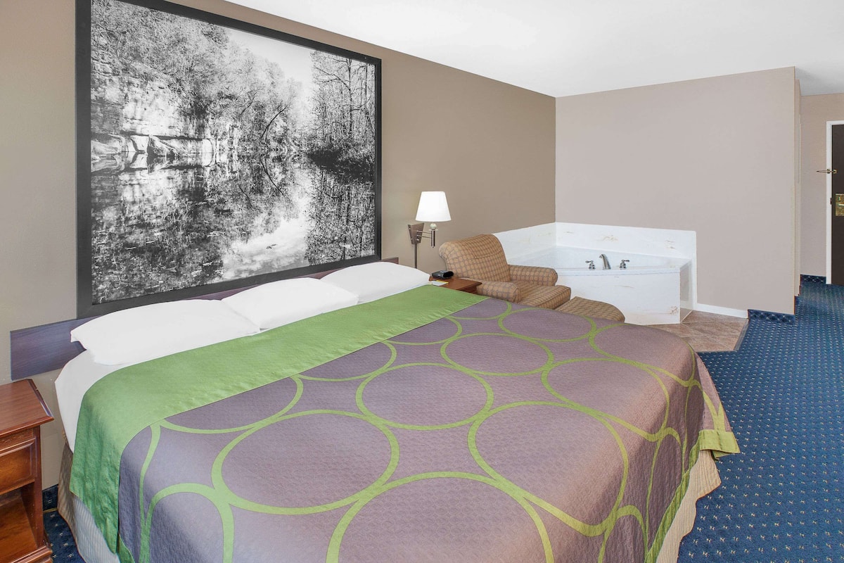 Ein Hotelzimmer mit einem großen Bett, einer Badewanne und einem an der Wand hängenden Kunstwerk.