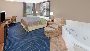 Une chambre d’hôtel équipée d’un lit, d’un bureau, d’une chaise, d’un canapé, d’une baignoire et d’une fenêtre avec des rideaux.