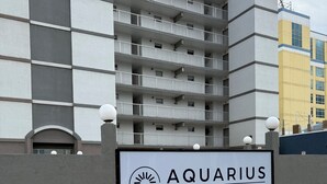 Skilt for Aquarius Hotel med en moderne bygning i baggrunden.