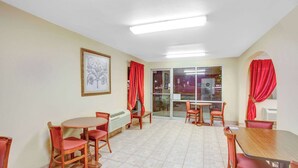 A dining area with a round table and chairs, a radiator, and a framed picture on the wall. - Baymont by Wyndham Coalinga (Coalinga)