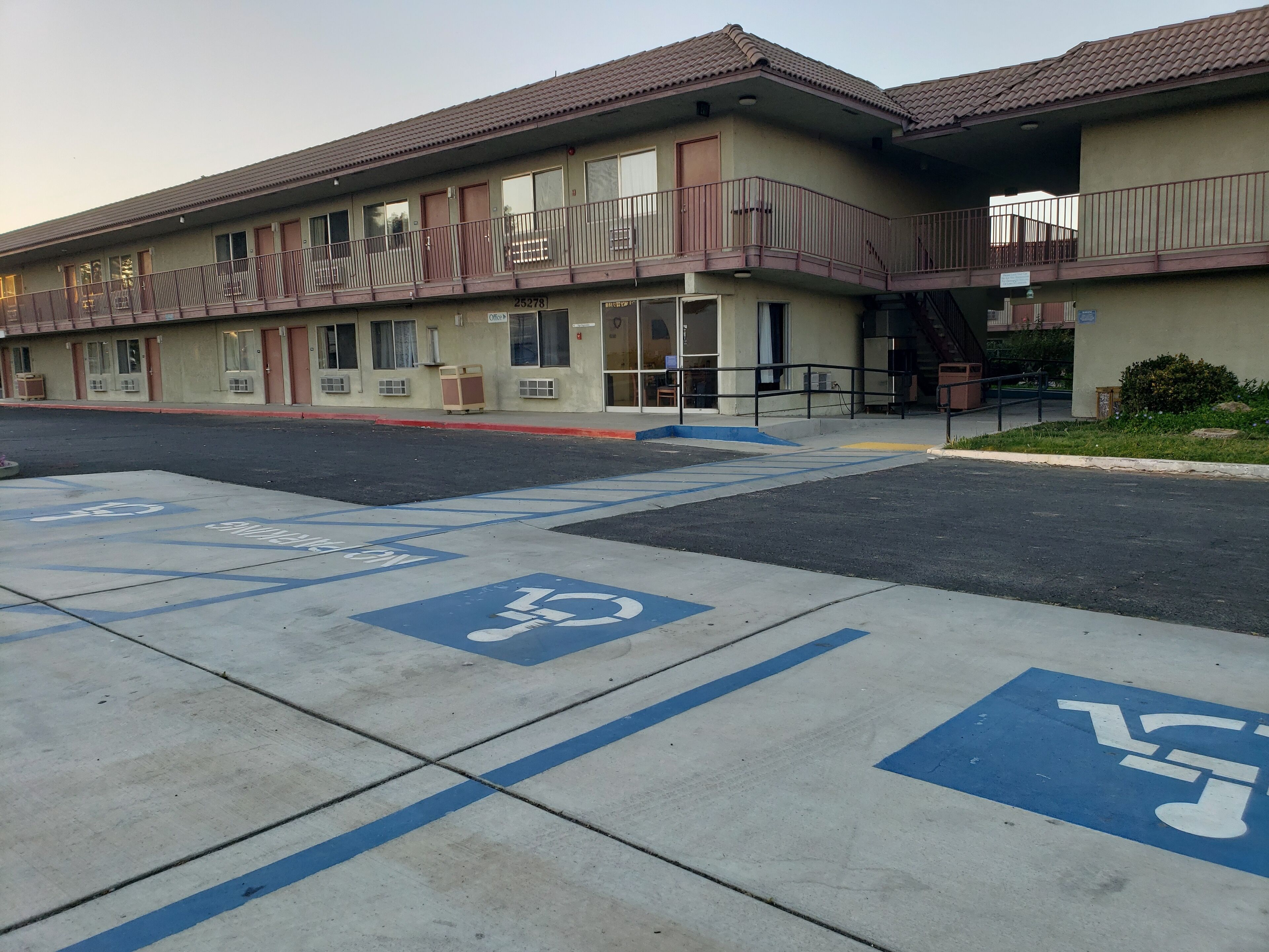 A building with a parking lot marked for disabled parking, a fire hydrant, and a sign indicating the number 25278.