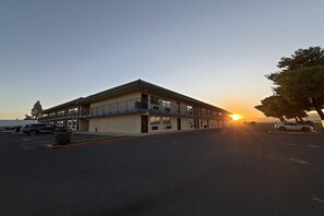 A motel with a flat roof, multiple windows, and a parking lot.