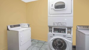 A laundry room with stacked washers and dryers, a control panel, and a window. - Baymont by Wyndham Coalinga (Coalinga)