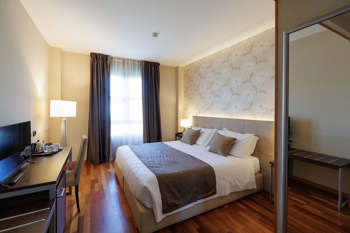 Ein Hotelzimmer mit Bett, Schreibtisch, Stuhl und Fernseher.